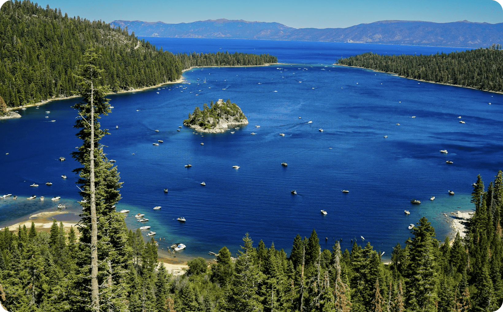 Lake with boats surrounded by forested hills.