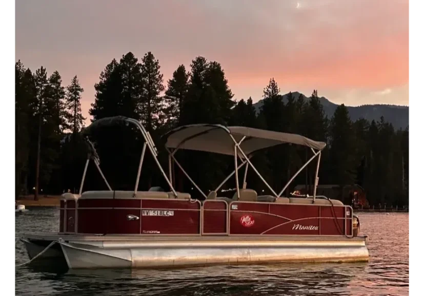 Pontoon boat on lake at sunset.