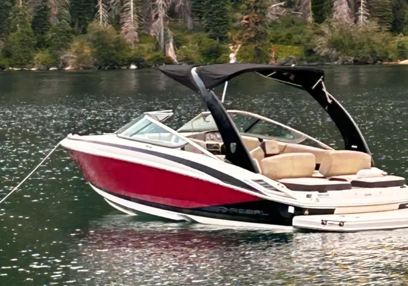 Red and white speedboat on calm lake.