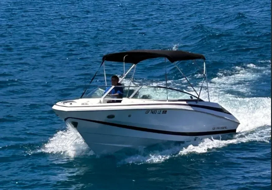 Person driving a speedboat on blue water.