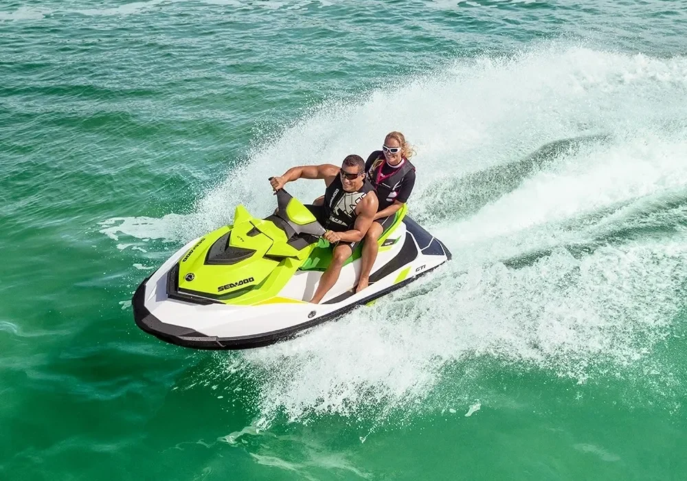 Two people riding a green jet ski.