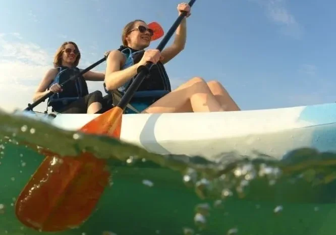 Two women kayaking on calm water.